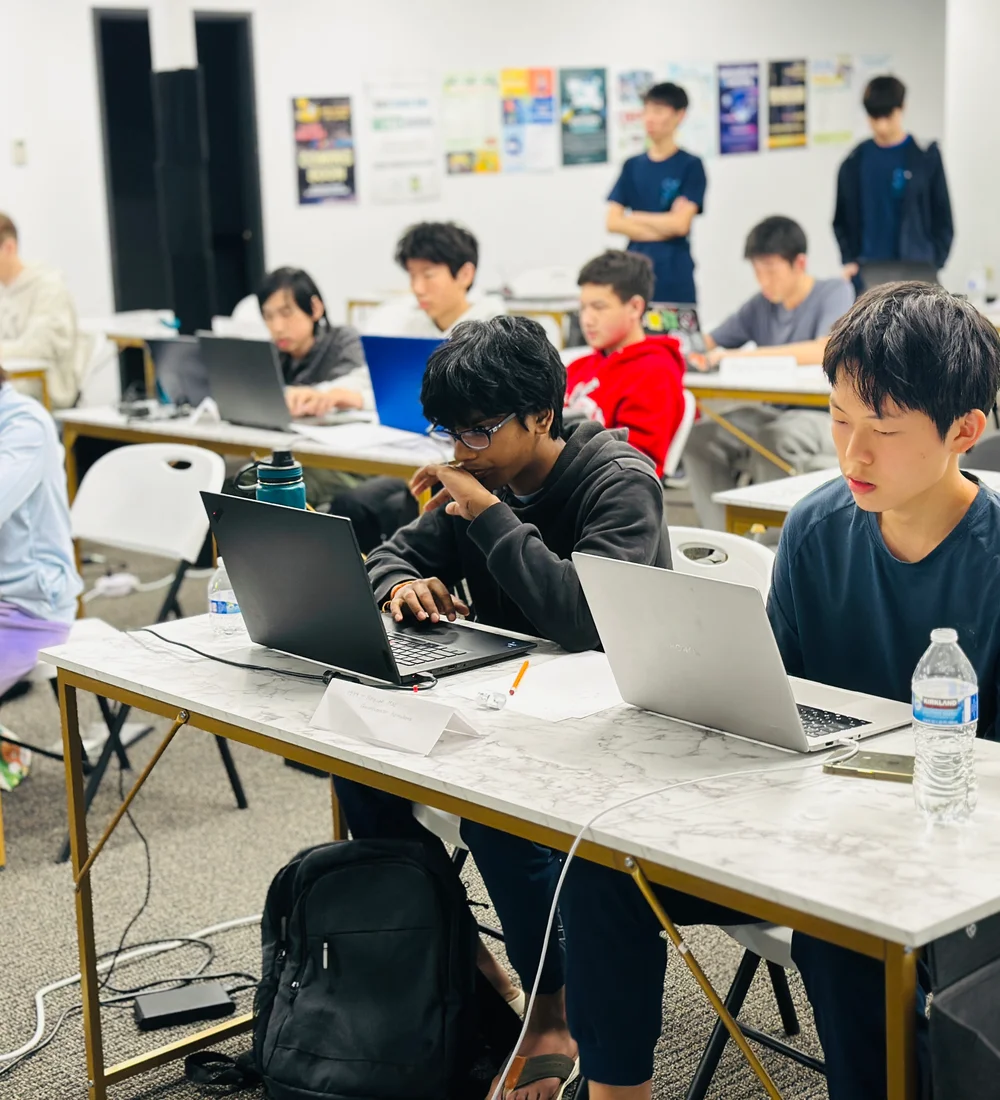 SACC competitors discussing a programming problem around their laptops